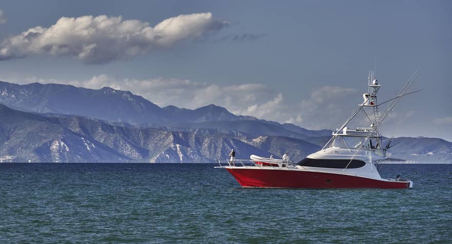 A white and red boat on the water with mountains in the distance.