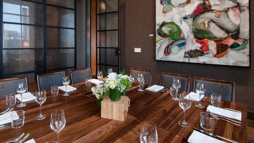 Dining table with a flower bouquet and wine glasses setting the table.